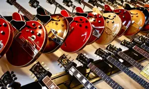 Rząd gitar elektrycznych w różnych kolorach i kształtach, od klasycznych po nowoczesne.