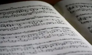 Położenie nut na pięciolinii w otwartej księdze. Nuty tworzą melodię, czekając na wykonanie.