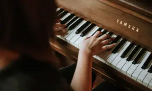 Dłonie na klawiaturze pianina Yamaha. Rozpoczyna się nauka gry na pianinie online, odkrywanie melodii.
