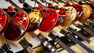 Rząd gitar elektrycznych w różnych kolorach i kształtach, od klasycznych po nowoczesne.