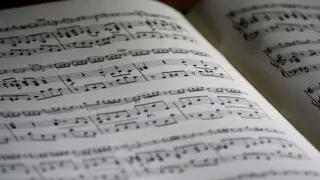 Położenie nut na pięciolinii w otwartej księdze. Nuty tworzą melodię, czekając na wykonanie.