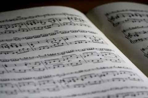 Położenie nut na pięciolinii w otwartej księdze. Nuty tworzą melodię, czekając na wykonanie.