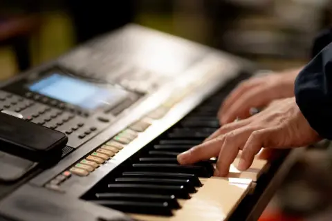 Dłonie grające na keyboardzie, który może być świetnym keyboardem dla dzieci.
