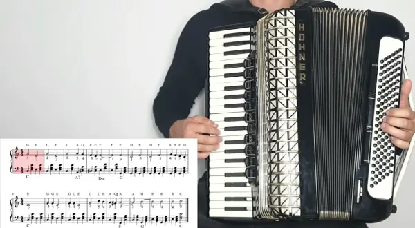 Akordeonista gra "Sto lat", nuty literowe pokazują melodię.