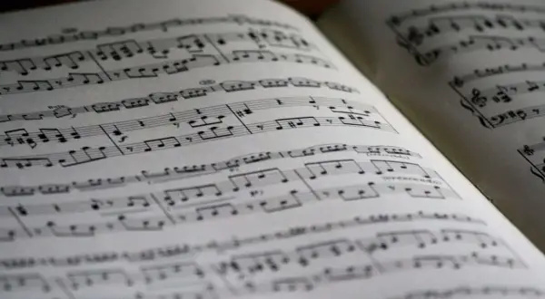 Położenie nut na pięciolinii w otwartej księdze. Nuty tworzą melodię, czekając na wykonanie.