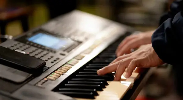 Dłonie grające na keyboardzie, który może być świetnym keyboardem dla dzieci.