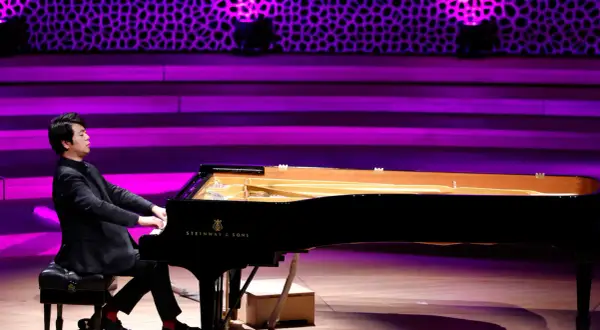 Pianista gra na czarnym fortepianie Steinway & Sons na scenie z fioletowym oświetleniem.