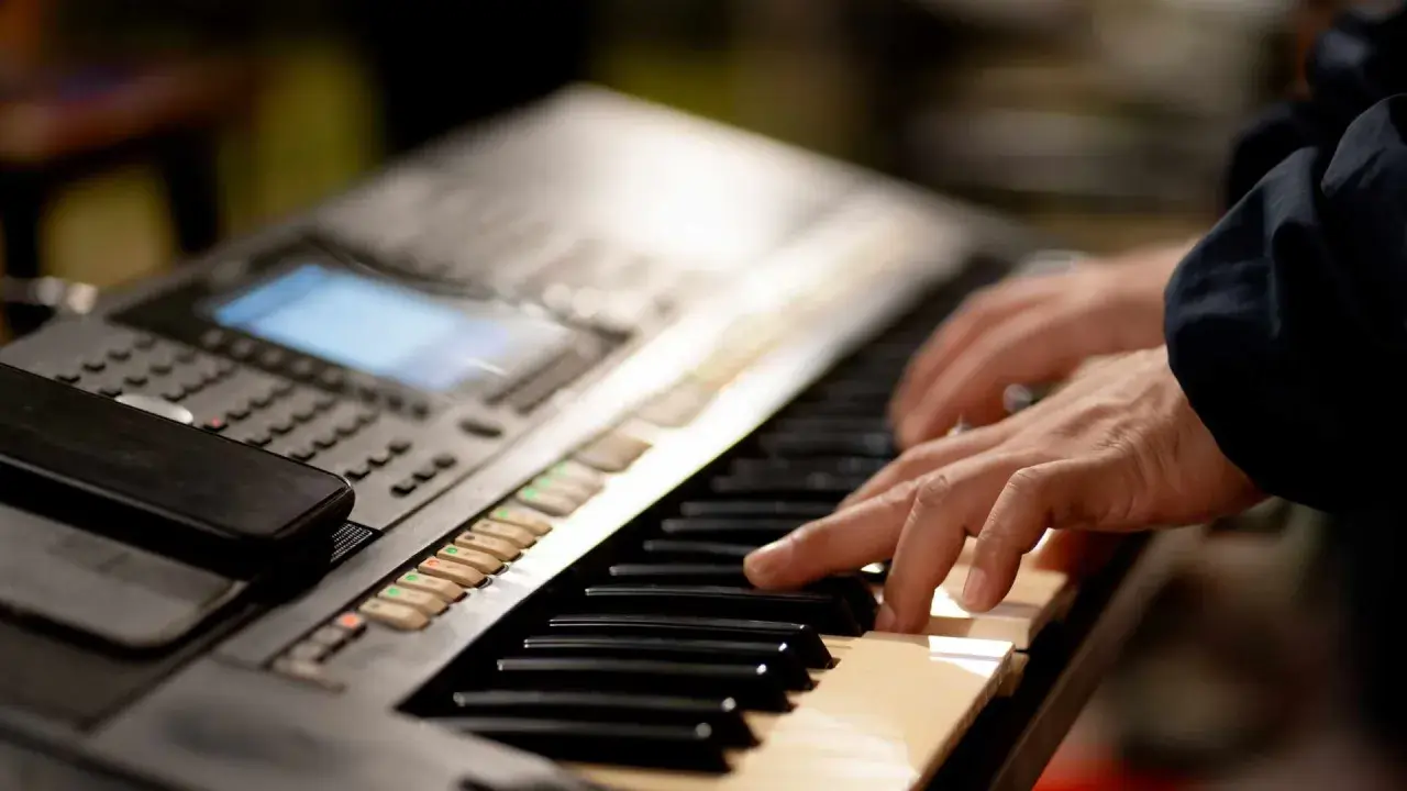 Dłonie grające na keyboardzie, który może być świetnym keyboardem dla dzieci.