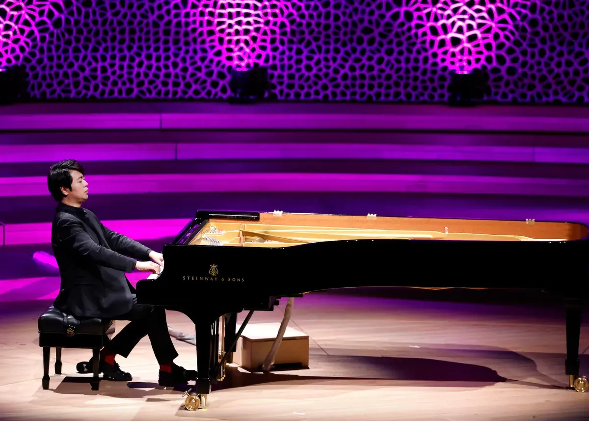 Pianista gra na czarnym fortepianie Steinway & Sons na scenie z fioletowym oświetleniem.