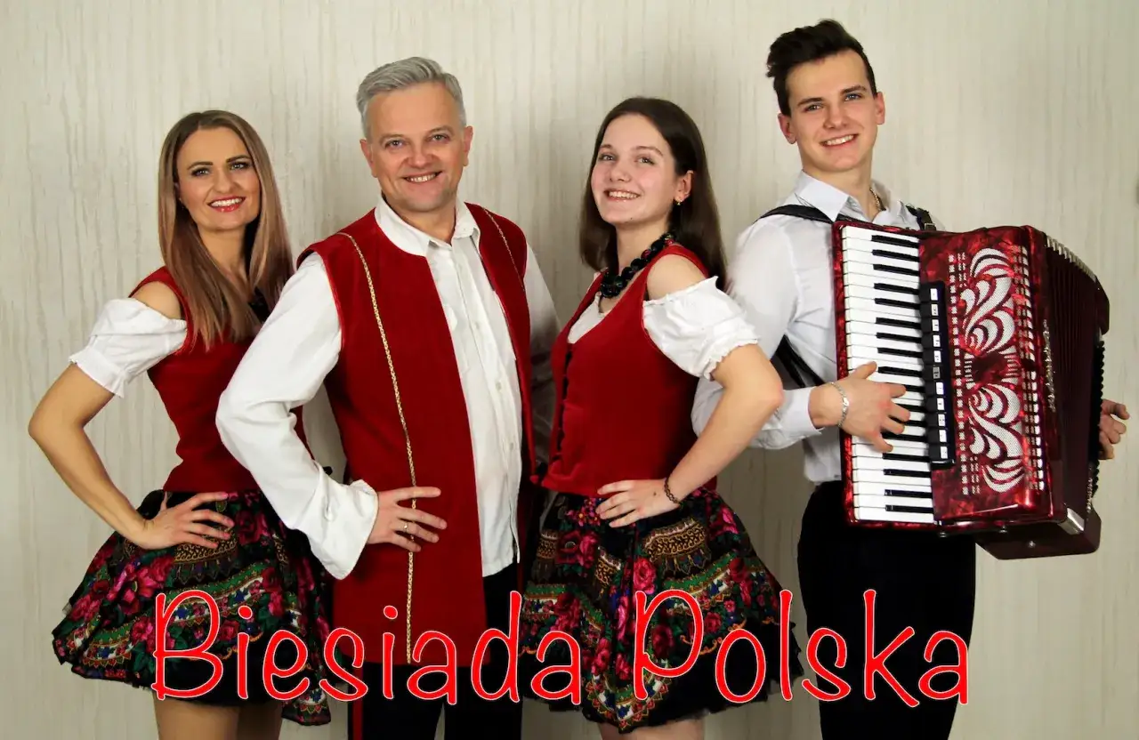 Zespół w strojach ludowych, młody mężczyzna gra na akordeonie. W tle napis 