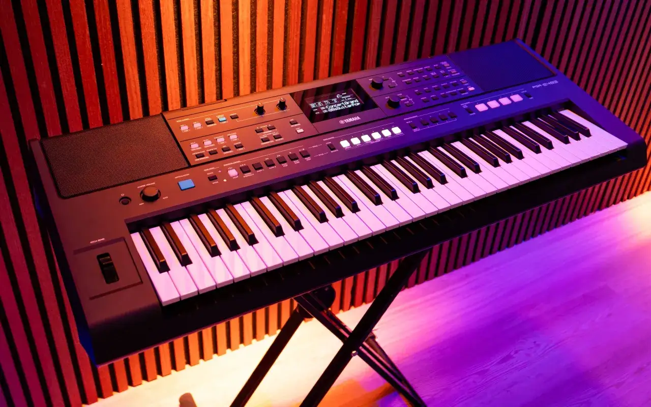 Czarny keyboard Yamaha PSR-E463 z dynamiczną klawiaturą, podświetlany na fioletowo, stoi na statywie.