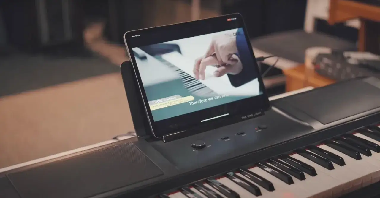 Nowa era nauki gry na pianinie. Tablet z lekcją Lang Langa nad klawiaturą cyfrowego pianina.