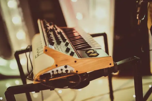 Drewniany stojak na keyboard z czarnymi metalowymi elementami, gotowy do muzycznej sesji.