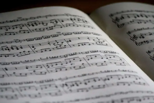 Położenie nut na pięciolinii w otwartej księdze. Nuty tworzą melodię, czekając na wykonanie.